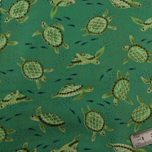 May include: Green fabric featuring a repeating pattern of sea turtles and small blue fish. The turtles have detailed shell patterns and are in various swimming poses. The background is a solid, medium green colour.