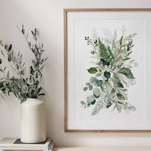 May include: A framed watercolour print of a green floral bouquet with white flowers and blue berries. The bouquet is arranged in a loose, natural style and is set against a white background.
