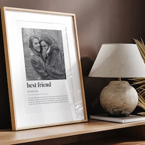 May include: A black and white photo of two friends in a framed print. The print has the word "best friend" and a definition of the word. The definition reads: "An irreplaceable person who makes the world a better place, someone who is by your side throughout all of life's ups and downs, no matter what troubles you face. A person who accepts your weirdness and loves you unconditionally, someone who laughs with you and cries with you. The best thing you can have and the best thing you can be."