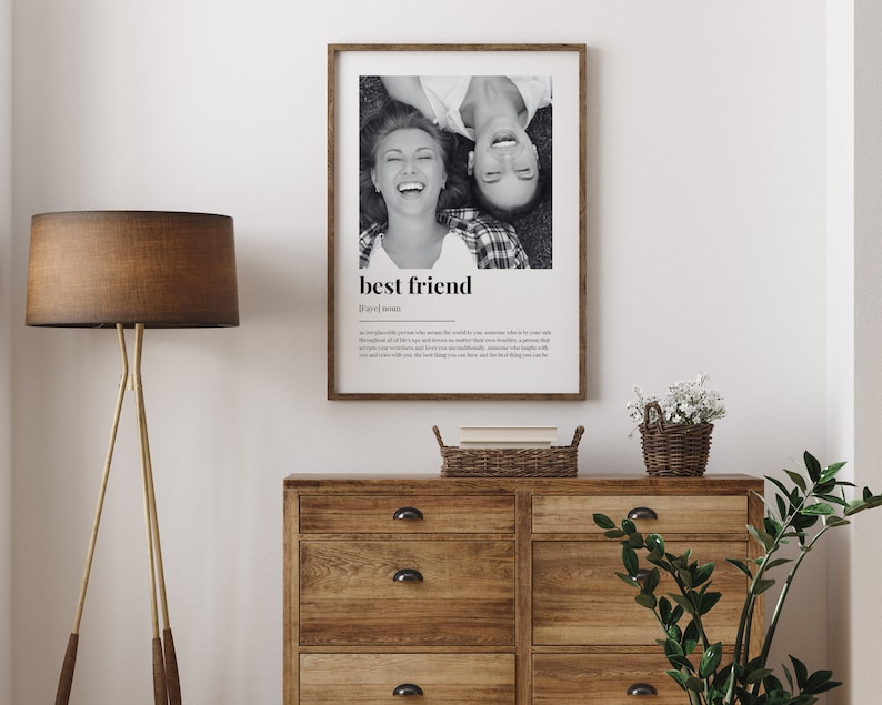 May include: Black and white photo of two friends laughing, printed on a white poster with the text "best friend" and a definition of the word. The poster is framed in a light wood frame.