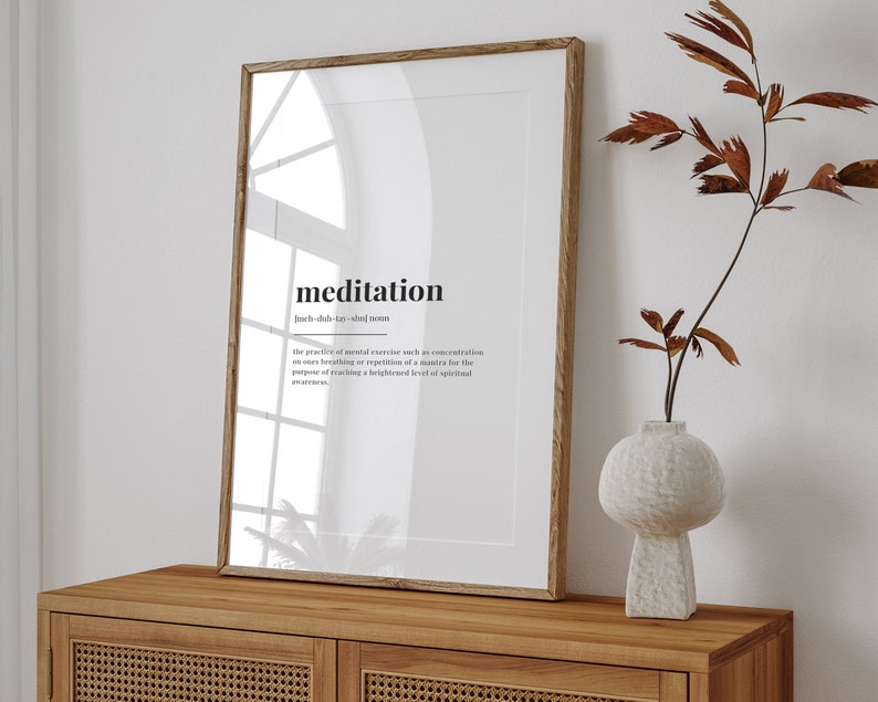 Peut inclure: Une impression encadr&eacute;e avec un fond blanc et du texte noir qui dit "meditation" et sa d&eacute;finition. L'impression est sur une table en bois avec un vase de branches s&eacute;ch&eacute;es.