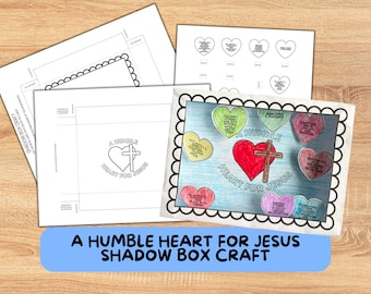 May include: A craft kit for a shadow box project with the text "A Humble Heart for Jesus." The image includes templates, a finished example with a red heart and cross, and heart-shaped notes with inspirational messages. The background is a light wood grain.