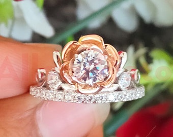 以下が含まれることがあります： バラゴールドとシルバーのリングで、大きなクリアな丸い宝石が花の形をしたクラウンにセットされています。リングは小さな宝石で囲まれています。