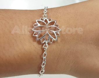 May include: A silver bracelet with a delicate, openwork flower charm. The charm is a stylized lotus flower with a circular shape and intricate details.