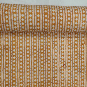 May include: A yellow and white kantha quilt with a repeating pattern of small diamonds and vertical lines. The quilt is folded in half and is lying on a white surface.