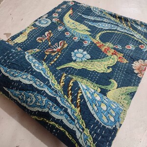 May include: A dark blue Kantha quilt with a repeating pattern of birds, flowers, and foliage in shades of yellow, green, red, and blue. The quilt is hand-stitched with white thread, creating a textured surface. The edges are neatly finished.