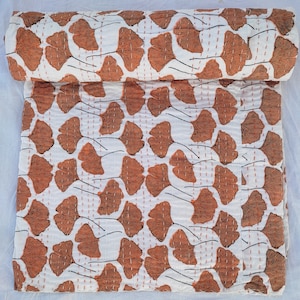 May include: A white cotton kantha quilt with a brown ginkgo leaf pattern. The quilt is hand-stitched and has a traditional Indian design.