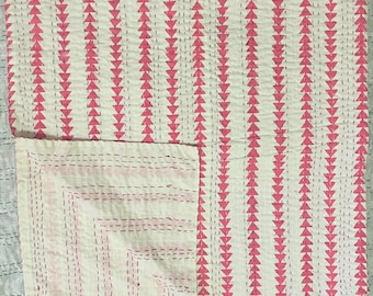 May include: A white cotton quilt with a pink triangle pattern. The quilt is folded in half and the stitching is visible.