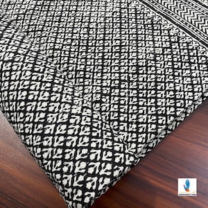 May include: Black and white cotton fabric with a repeating geometric pattern of small white leaves on a black background.