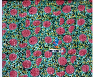 Könnte beinhalten: Eine grün-rosa Blumensteppdecke mit einem sich wiederholenden Muster aus großen rosa Blüten und grünen Blättern. Die Steppdecke hat einen floralen Rand und den Text "SAAVISINCE1988". Der Stoff ist weich und gesteppt.