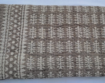 Puede incluir: Una colcha kantha gris con un patrón floral blanco. La colcha está cosida a mano y tiene un diseño tradicional indio.