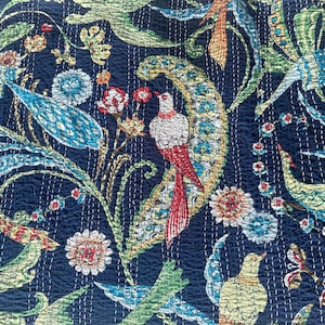 May include: Navy blue fabric with a detailed floral and bird pattern. The design features birds with red and white plumage, along with flowers and foliage in shades of blue, green, and orange. The fabric has a quilted texture.