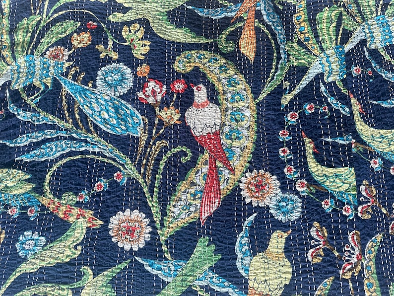 May include: Navy blue fabric with a detailed floral and bird pattern. The design features birds with red and white plumage, along with flowers and foliage in shades of blue, green, and orange. The fabric has a quilted texture.