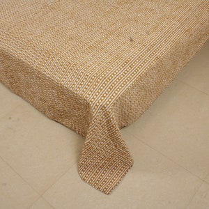 May include: A brown and white patterned quilt with a textured surface. The quilt is folded and draped over a bed.