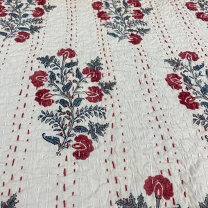 Può includere: Tessuto color crema con un motivo floreale ripetuto in bordeaux e grigio. I fiori sono stilizzati, con foglie e petali dettagliati. Il tessuto è cucito con un motivo a pois, aggiungendo consistenza.