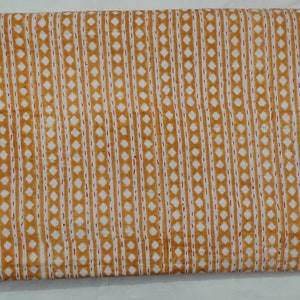 May include: A yellow and white fabric with a repeating pattern of small diamonds and thin lines. The fabric has a subtle texture and a slightly faded look.