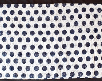 May include: White and navy blue polka dot quilt. The quilt features a repeating pattern of large navy blue circles on a white background. The quilt is hand-stitched with white thread, creating a textured surface.