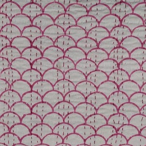 May include: White fabric with a repeating pattern of pink, semi-circular shapes, resembling a scale design. The design is stitched with pink thread, creating a textured surface. The overall aesthetic is simple and elegant.