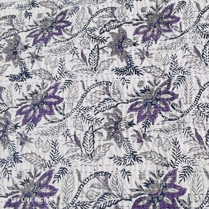 May include: A white textile with a repeating floral pattern in shades of purple, gray, and dark blue. The design features large stylized flowers and leafy vines, all stitched onto the fabric. The overall aesthetic is a blend of botanical and geometric elements.