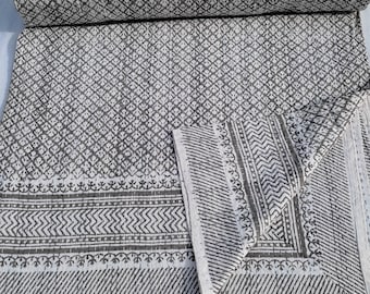Puede incluir: Un edredón enrollado con estampado gris y blanco con un diseño geométrico. El edredón está hecho de tela suave y presenta un patrón floral repetitivo. El edredón está doblado y listo para usar.
