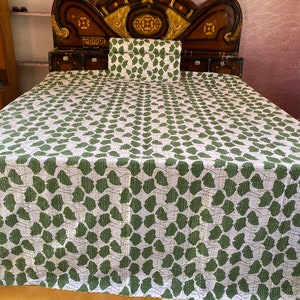 May include: A white bedspread and matching rectangular pillow sham featuring a repeating green ginkgo leaf pattern. The fabric displays visible linear stitching throughout, creating a textured appearance across the entire surface of the bedding set.