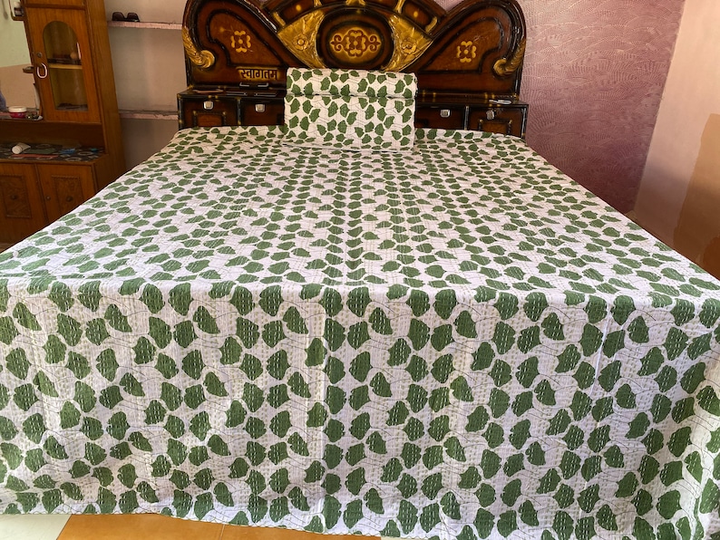 May include: A white bedspread and matching rectangular pillow sham featuring a repeating green ginkgo leaf pattern. The fabric displays visible linear stitching throughout, creating a textured appearance across the entire surface of the bedding set.