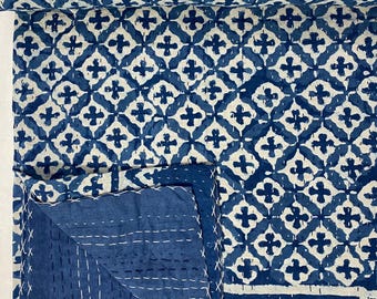 Könnte beinhalten: Eine blaue und weiße Kantha-Steppdecke mit geometrischem Muster. Die Decke ist in der Hälfte gefaltet und die Nähte sind sichtbar.