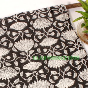 May include: Black fabric with a white floral pattern. The fabric has a repeating pattern of stylized flowers and leaves.