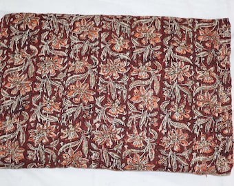 May include: A brown kantha quilt with a floral pattern in shades of orange, white, and brown. The quilt is made of cotton and is hand-stitched.