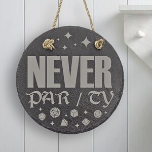 May include: A round, black slate sign with a rope hanger. The sign says "NEVER PARTY" in a stylized font. The sign is decorated with small, silver stars and dice.
