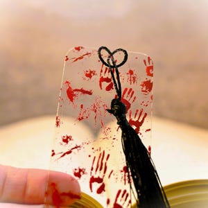 May include: A clear plastic bookmark with red handprint designs and a black tassel.