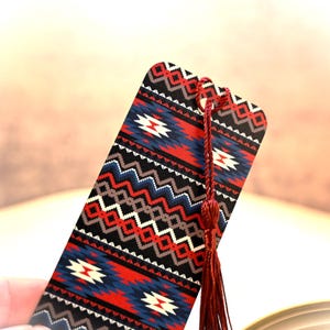 May include: A red, blue, white, and black patterned bookmark with a red tassel. The bookmark has a geometric design.
