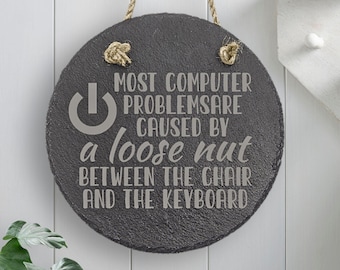 May include: A round, black slate sign with a rope hanger. The sign has a white power button symbol and the text "MOST COMPUTER PROBLEMSARE CAUSED BY a loose nut BETWEEN THE CHAIR AND THE KEYBOARD".