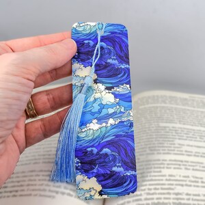 May include: Blue and white bookmark with a wave pattern and a light blue tassel. The bookmark is made of a sturdy material and is perfect for marking your place in a book.