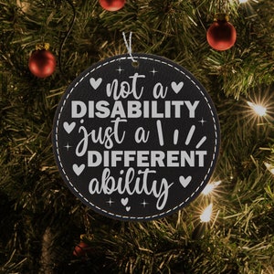 May include: Black and white Christmas ornament with the text "not a disability just a different ability" with hearts and stars around the text.