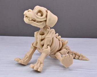 May include: A beige plastic skeleton of a dog sitting on a light wood surface. The dog's mouth is open and its eyes are large and round.