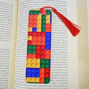 May include: A colorful bookmark featuring a pattern of red, yellow, blue, and green Lego bricks. The bookmark has a red tassel.
