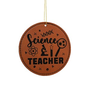 May include: Brown leather ornament with the text "Science Teacher" in black lettering. The ornament features a microscope, a beaker, a DNA strand, and a magnifying glass with a virus inside.