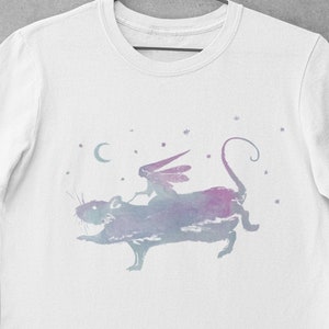 Puede incluir: Camiseta blanca con una ilustraci&oacute;n de acuarela de una hada montando una rata en un cielo estrellado.