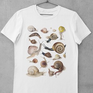 May include: White t-shirt with a print of various snails in different sizes and colors. The snails are arranged in a random pattern on the shirt.