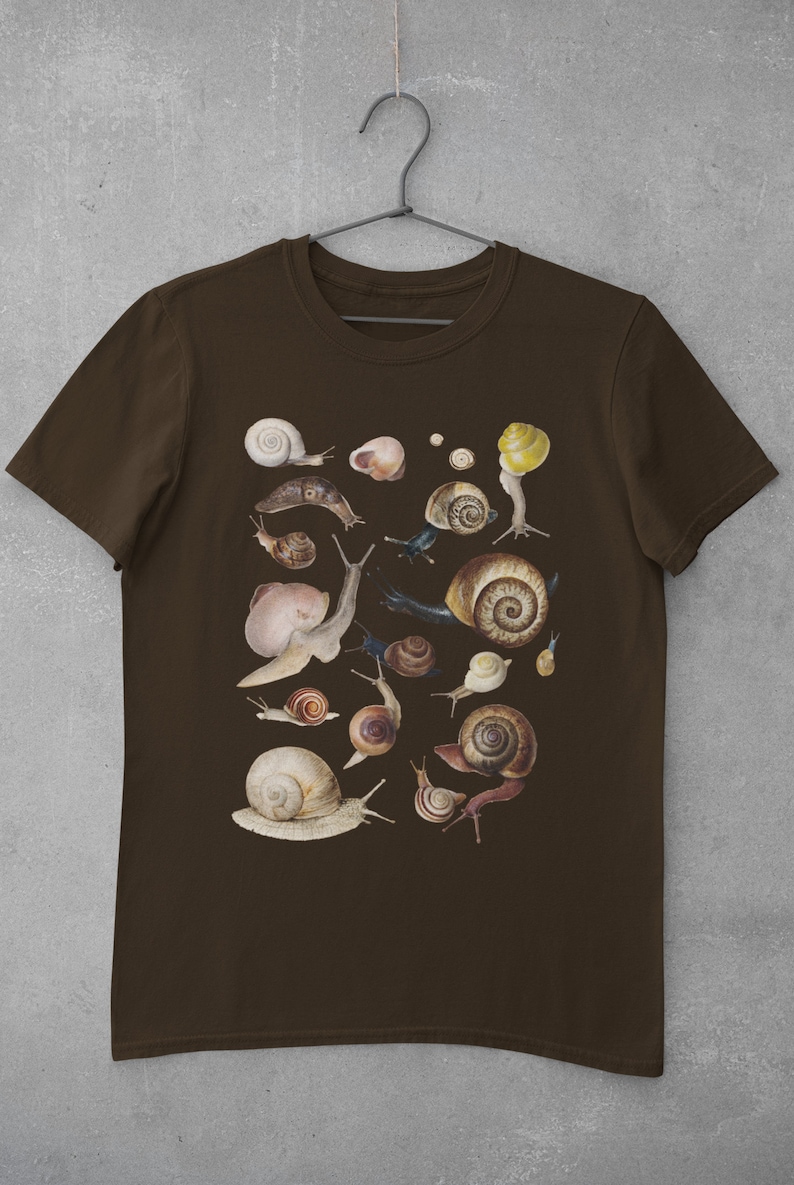 May include: A brown t-shirt with a print of various snails in different sizes and colors. The snails are arranged in a random pattern on the shirt.