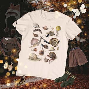May include: A white t-shirt with a print of various snails in different colors and sizes. The snails are arranged in a random pattern on the shirt.