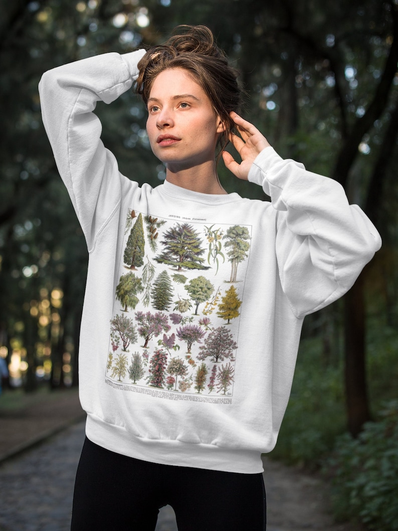 Puede incluir: Sudadera blanca con una ilustraci&oacute;n bot&aacute;nica vintage de varios &aacute;rboles y plantas. La ilustraci&oacute;n est&aacute; en tonos de verde, marr&oacute;n y rosa.
