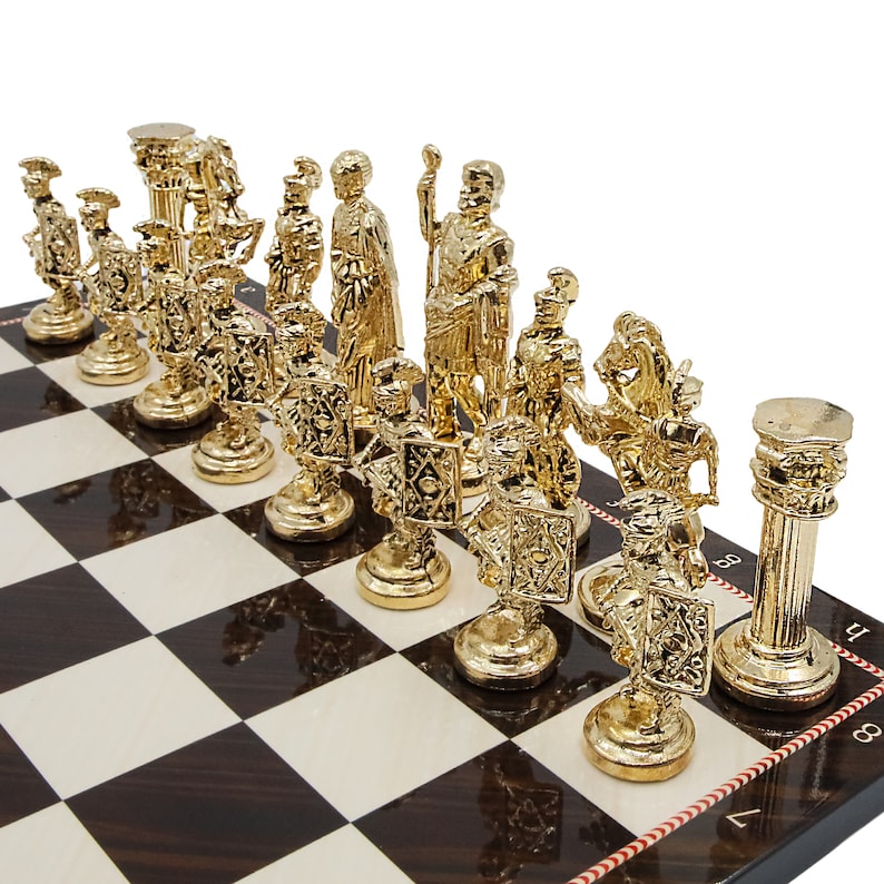 Op de afbeelding: Een gouden schaakset met Romeinse soldatenstukken op een houten schaakbord. De stukken zijn gedetailleerd en hebben een metalen afwerking.