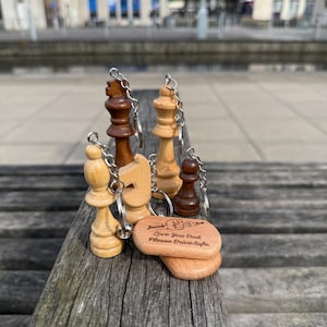 May include: A collection of wooden chess piece keychains in various colors, including light and dark brown, and natural wood tones. One keychain has the text "Jacob Love You Dad Please Drive Safe."