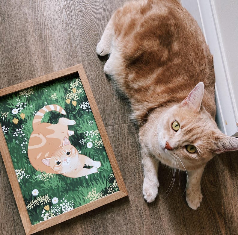 A photo of a cat next to their personalised print.