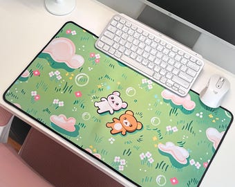 May include: A rectangular desk mat featuring a green meadow pattern with small pink and white flowers, light pink clouds, and two cartoon bears, one white and one brown, lying on the grass surrounded by translucent bubbles.