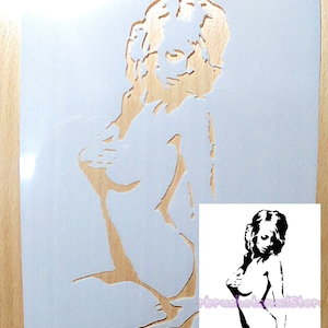 May include: A stencil of a woman's body in a nude pose. The stencil is made of wood and is hand-cut. The stencil is on a white background. The stencil is for use with paint or other mediums.