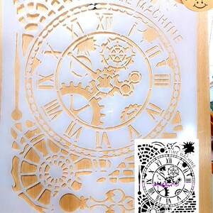 May include: A translucent plastic stencil sheet featuring a clock face design with Roman numerals, intricate internal gears, and mechanical components. The text "TIME MACHINE" is printed along the top arc of the clock. A small circular tag reads "Hand made".
