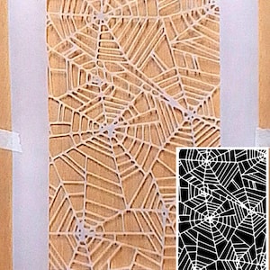 May include: A rectangular stencil featuring a repeating spider web pattern with intricate cutouts. The semi-transparent material is labeled with the text Durable LASER CUT Mylar. An inset shows the pattern in high-contrast black and white.